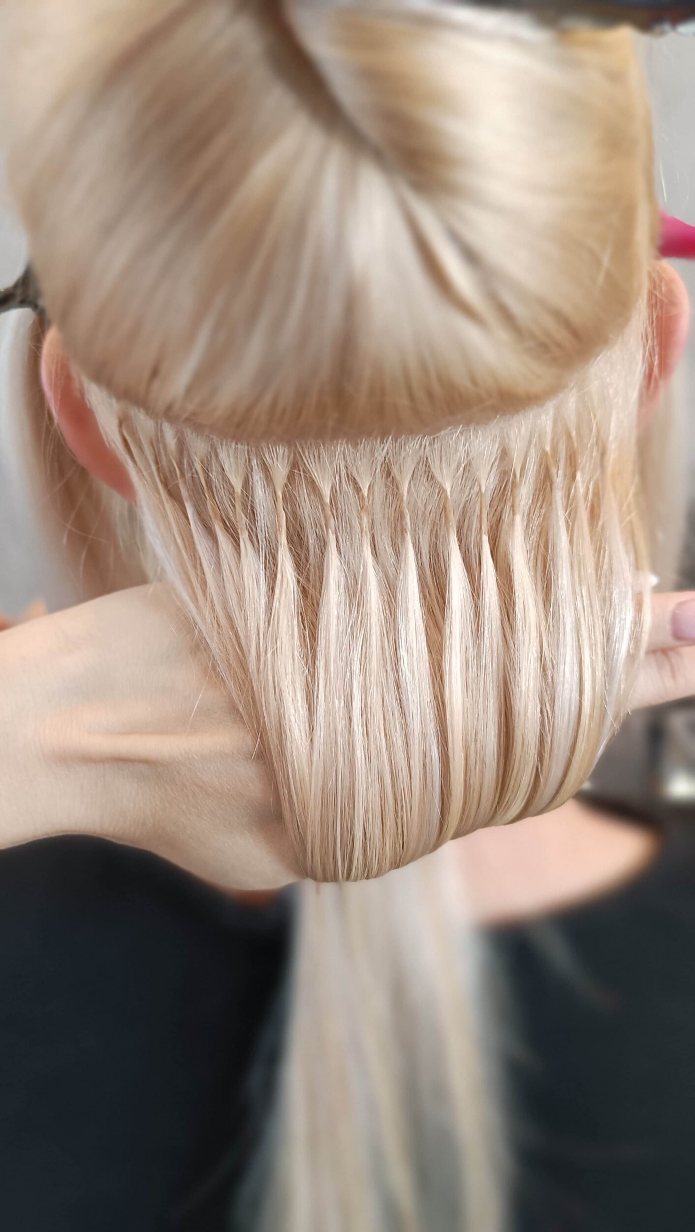Nahaufnahme von blonden Haaren mit eingesetzten Haarverlängerungen (Bondings) im Friseursalon.