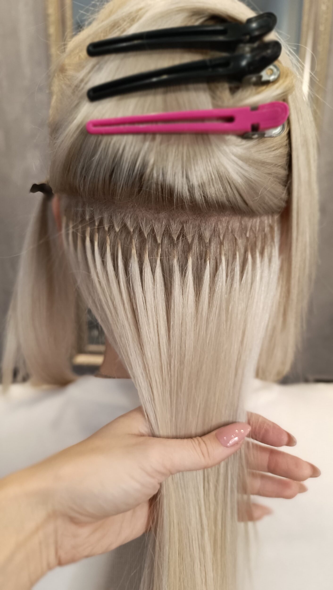 Blonde Frau bei der eben Extensions eingesetzt werde, extensions lange haare