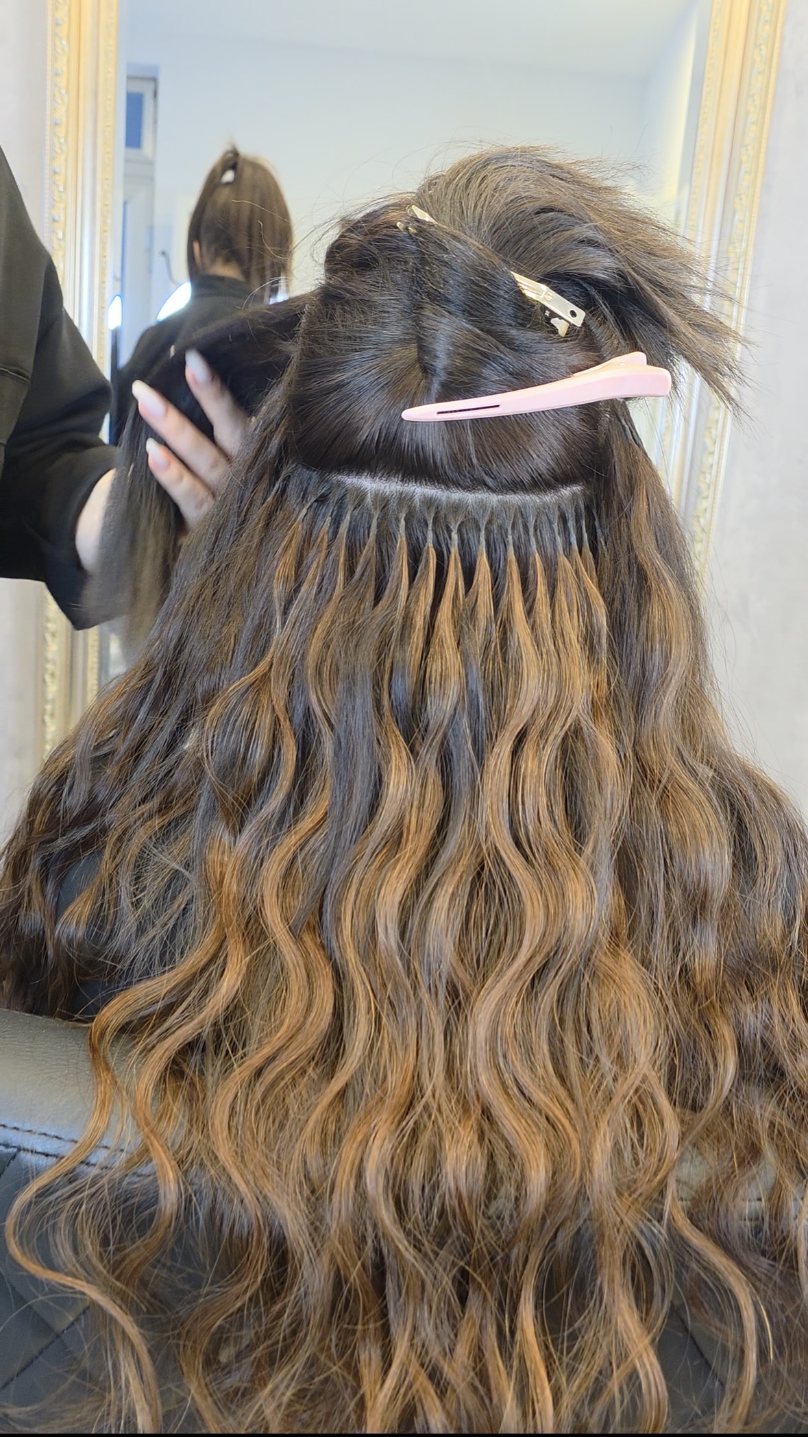 Friseurin beim Hochsetzen oder Nacharbeiten von Tape-Extensions.