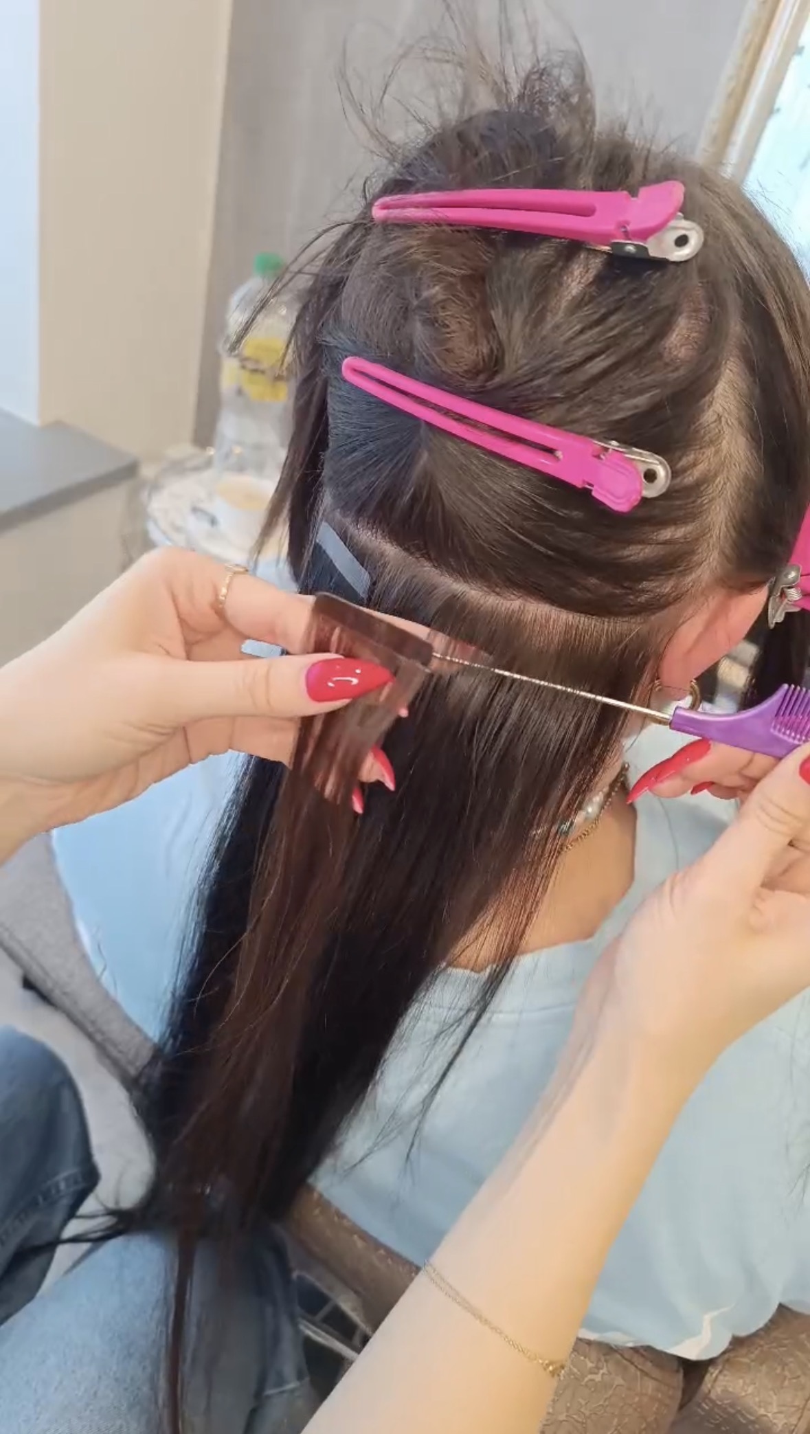 Friseurin entfernt Bondings oder löst Tape-Strähnen – Nahaufnahme der Hände.