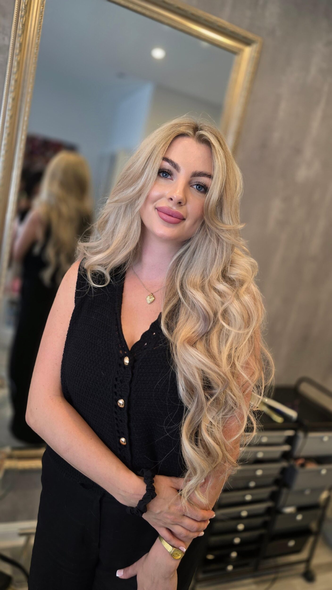 Frau mit vollem, glänzendem Haar schaut lächelnd in den Spiegel – Symbol für das Endergebnis einer Haarverdichtung.