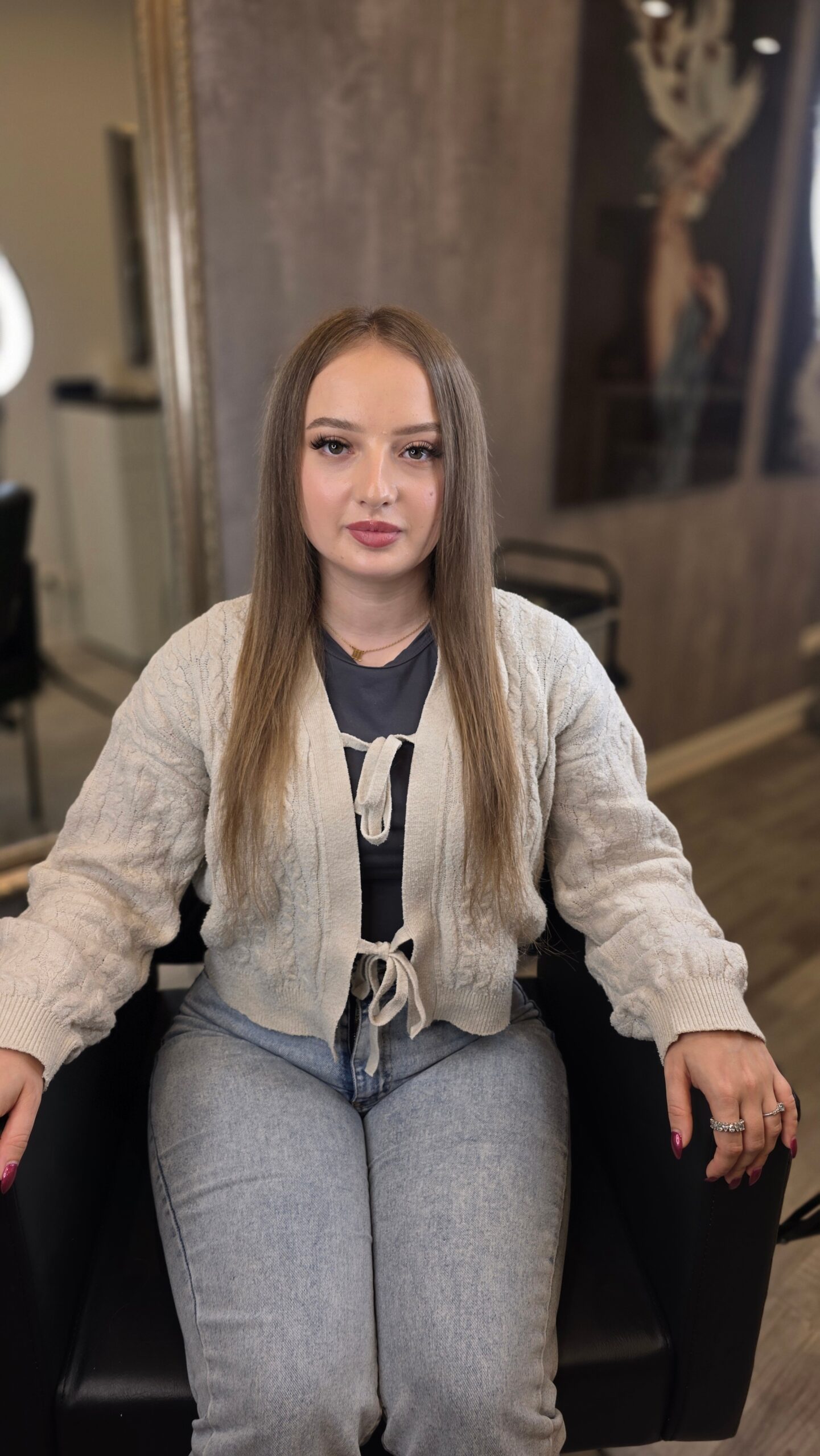Kundin im Friseurstuhl mit langen, gepflegten Haaren Friseur oder Friseurin beim Anbringen von Extensions Professionelle Atmosphäre, hochwertige Saloneinrichtung