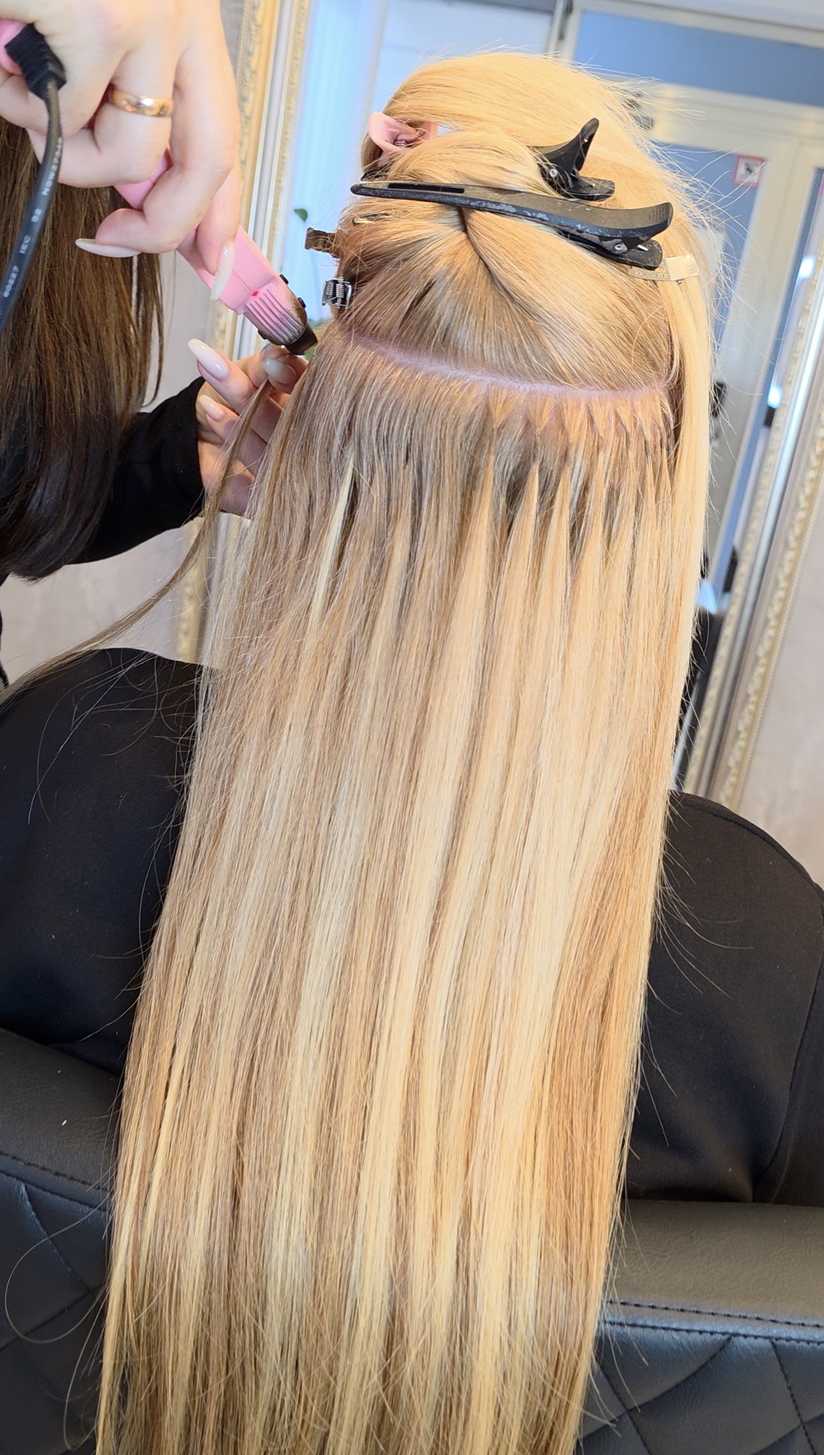 Einarbeitungsszene (z. B. Friseur befestigt Tape- oder Bonding-Extensions)Nahaufnahme der Hände und Werkzeuge – Fokus auf Präzision